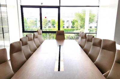 Miniature Location salle Croissy-Beaubourg (Seine-et-Marne) - La Mega Place #25 Vue aérienne d'un grand bâtiment moderne avec un parking rempli de voitures à l'avant et des arbres en arrière-plan.