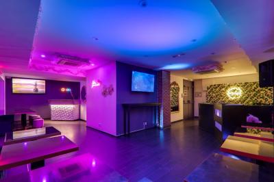 Façade d'un bar à bubble tea avec terrasse extérieure, tables et chaises en osier, éclairage nocturne.