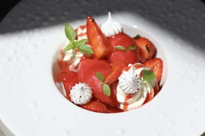 Dessert composé de fraises fraîches, sorbet, crème chantilly et petites feuilles de basilic dans une assiette blanche.