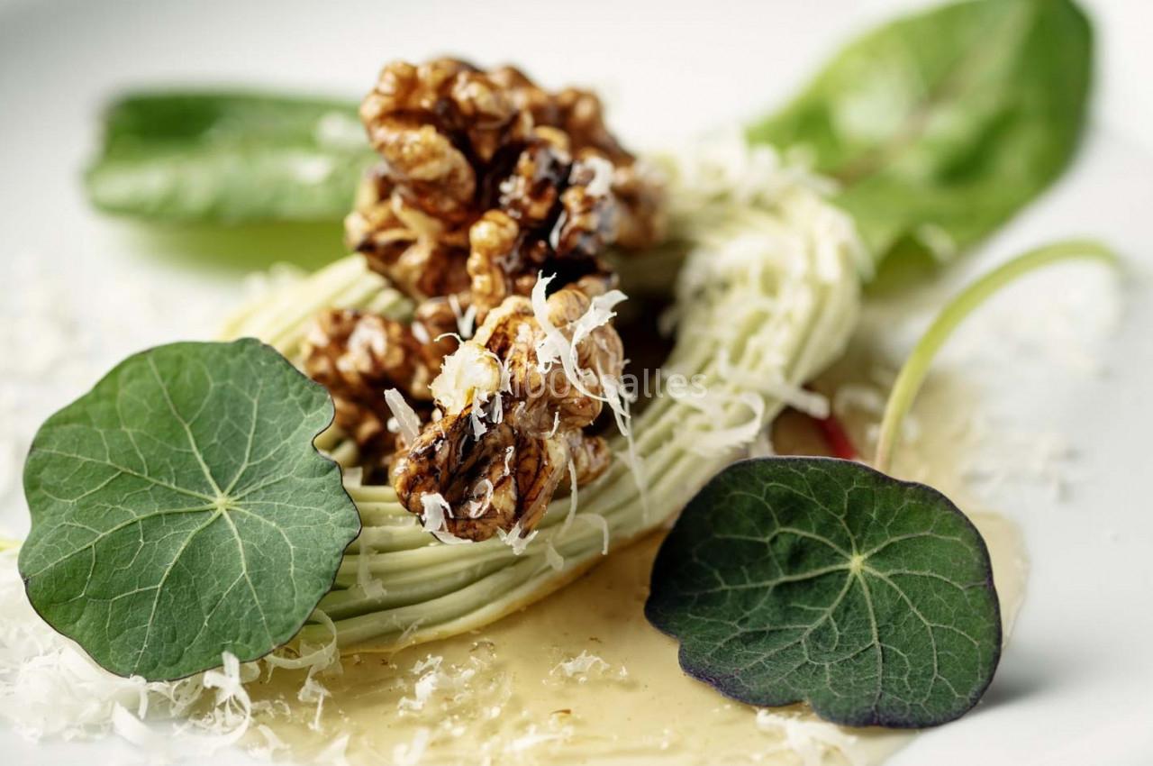 Assiette garnie de spaghettis de légumes, noix caramélisées, feuilles de capucine et copeaux de fromage.