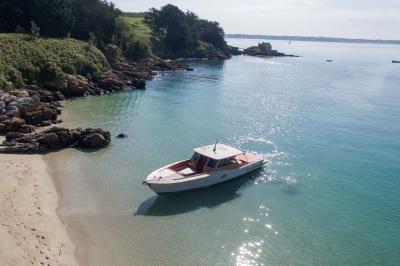 Chambre lumineuse avec lit double, bureau en bois, lampe et rideaux colorés près de fenêtres donnant sur l'extérieur.