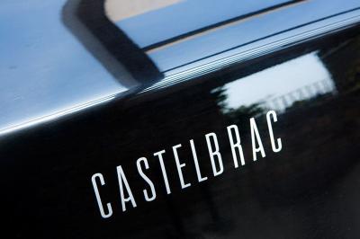 Chambre lumineuse avec lit double, bureau en bois, lampe et rideaux colorés près de fenêtres donnant sur l'extérieur.