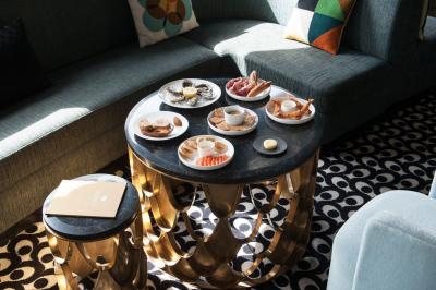 Chambre lumineuse avec lit double, bureau en bois, lampe et rideaux colorés près de fenêtres donnant sur l'extérieur.