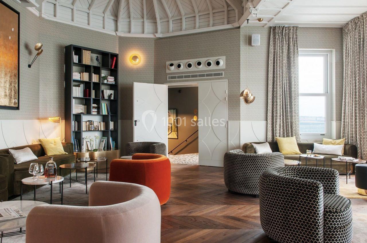 Salon élégant avec fauteuils variés, bibliothèque, éclairage design et vue sur une fenêtre donnant sur l'extérieur.