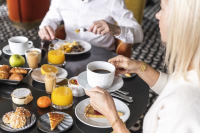 Chambre lumineuse avec lit double, bureau en bois, lampe et rideaux colorés près de fenêtres donnant sur l'extérieur.