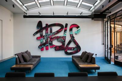 Salle de réunion moderne avec table noire, chaises, écran mural, tableau blanc et éclairage encastré.