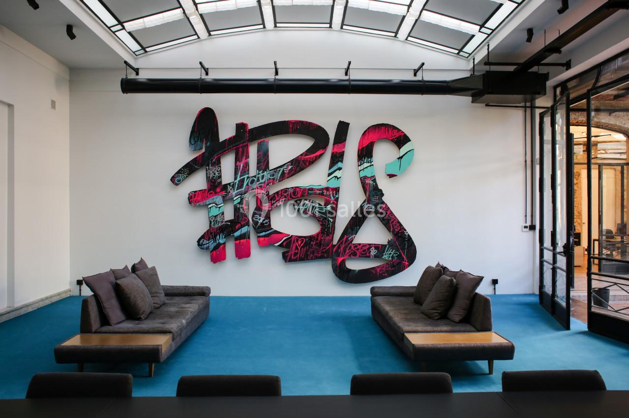 Mur décoré d'une grande sculpture murale colorée dans un espace moderne avec canapés et lumière naturelle.