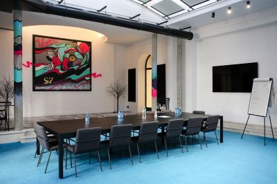 Salle de réunion moderne avec table noire, chaises, écran mural, tableau blanc et éclairage encastré.