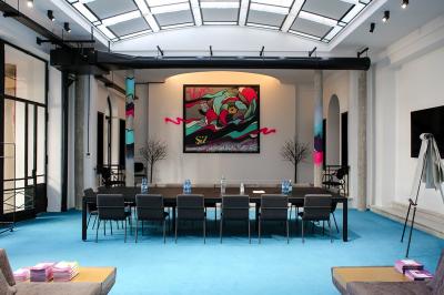 Salle de réunion moderne avec table noire, chaises, écran mural, tableau blanc et éclairage encastré.