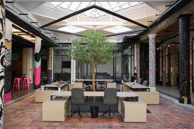 Salle de réunion moderne avec table noire, chaises, écran mural, tableau blanc et éclairage encastré.