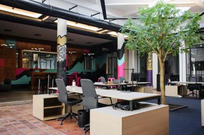 Salle de réunion moderne avec table noire, chaises, écran mural, tableau blanc et éclairage encastré.