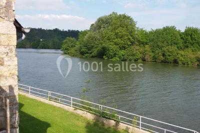 Salle de réception décorée avec des tables rondes dressées, des lanternes suspendues et un éclairage tamisé.