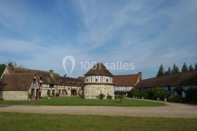 Salle de réception décorée avec des tables rondes dressées, des lanternes suspendues et un éclairage tamisé.