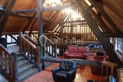 Salle de réception décorée avec des tables rondes dressées, des lanternes suspendues et un éclairage tamisé.