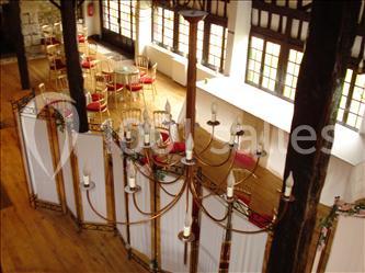 Salle de réception décorée avec des tables rondes dressées, des lanternes suspendues et un éclairage tamisé.
