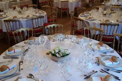 Salle de réception décorée avec des tables rondes dressées, des lanternes suspendues et un éclairage tamisé.