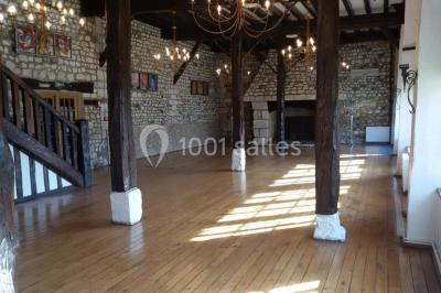 Salle de réception décorée avec des tables rondes dressées, des lanternes suspendues et un éclairage tamisé.