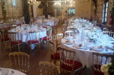 Salle de réception décorée avec des tables rondes dressées, des lanternes suspendues et un éclairage tamisé.