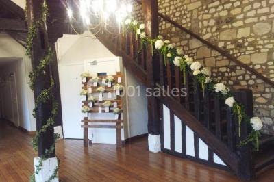 Salle de réception décorée avec des tables rondes dressées, des lanternes suspendues et un éclairage tamisé.