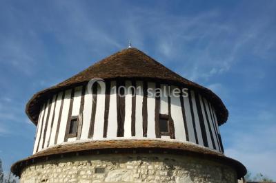 Salle de réception décorée avec des tables rondes dressées, des lanternes suspendues et un éclairage tamisé.