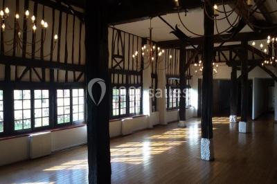 Salle de réception décorée avec des tables rondes dressées, des lanternes suspendues et un éclairage tamisé.
