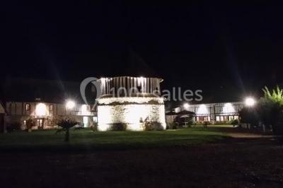 Salle de réception décorée avec des tables rondes dressées, des lanternes suspendues et un éclairage tamisé.