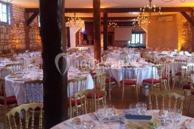 Salle de réception décorée avec des tables rondes dressées, des lanternes suspendues et un éclairage tamisé.