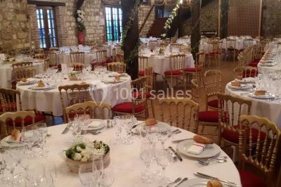 Salle de réception décorée avec des tables rondes dressées, des lanternes suspendues et un éclairage tamisé.