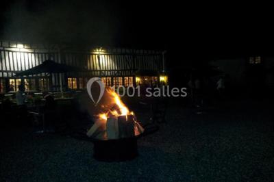 Salle de réception décorée avec des tables rondes dressées, des lanternes suspendues et un éclairage tamisé.