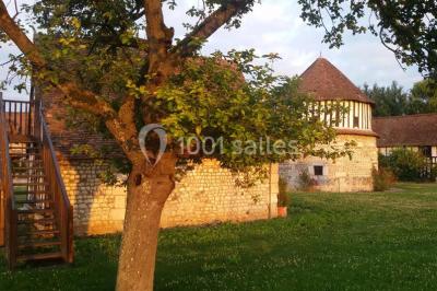 Salle de réception décorée avec des tables rondes dressées, des lanternes suspendues et un éclairage tamisé.