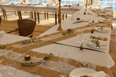 Une femme lit un discours devant un couple assis sous une arche décorée, lors d'une cérémonie en extérieur.