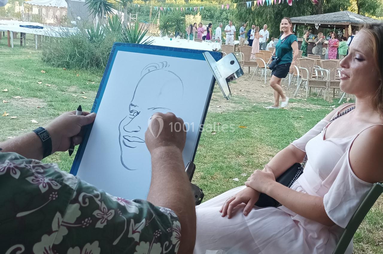 Un artiste dessine le portrait d'une femme assise en extérieur lors d'un événement en plein air.