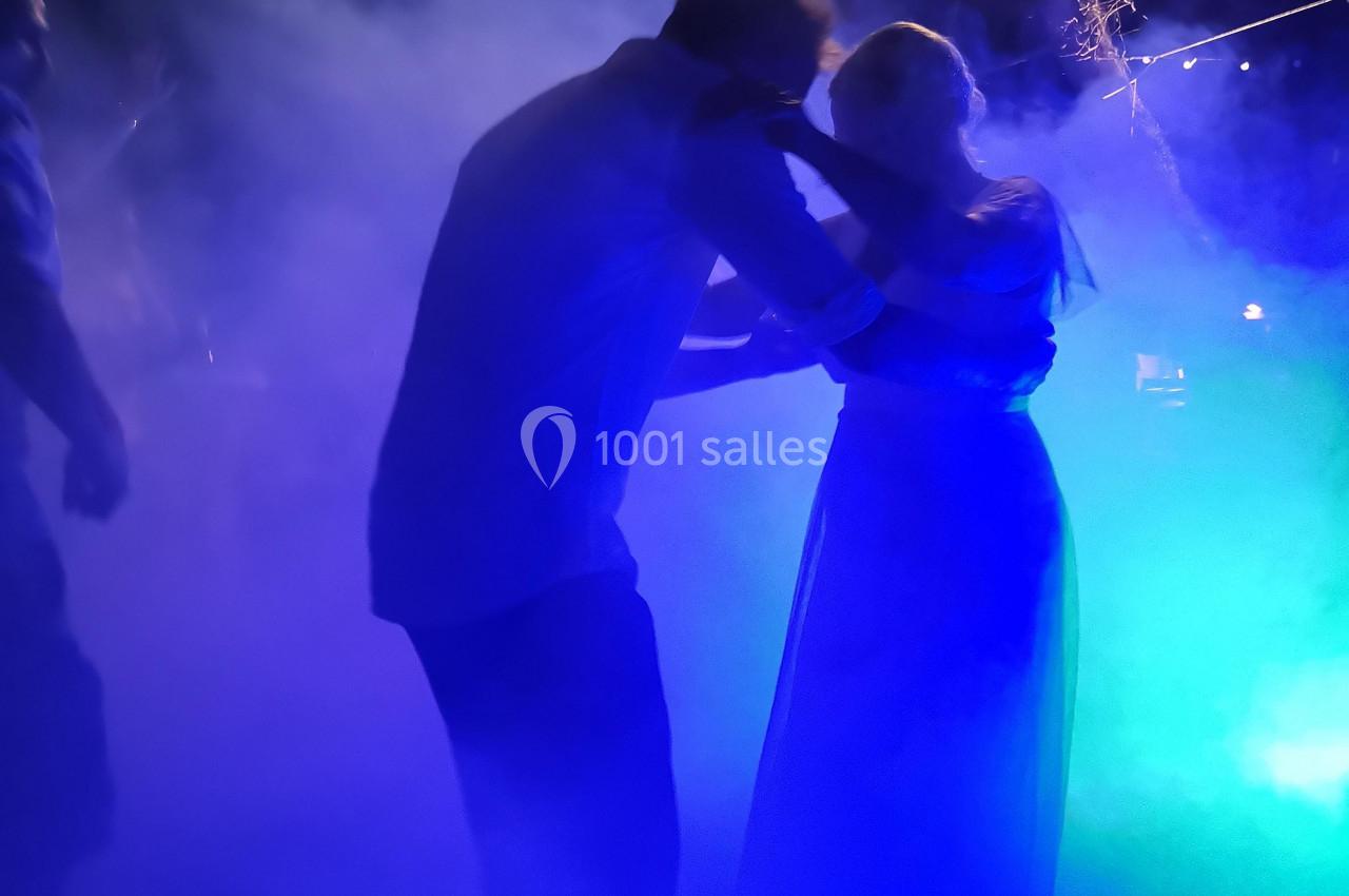 Un couple danse dans une ambiance nocturne éclairée par des lumières colorées et entourée de fumée.