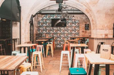 Cabine photo vintage avec rideaux rouges, entourée de tabourets empilés et d'un distributeur automatique rouge.