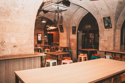 Cabine photo vintage avec rideaux rouges, entourée de tabourets empilés et d'un distributeur automatique rouge.