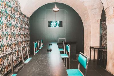 Salle voûtée en pierre avec des tables hautes, des tabourets colorés et un éclairage tamisé.