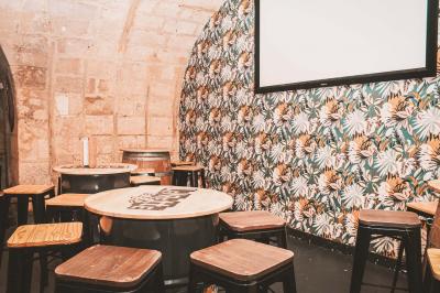 Salle voûtée en pierre avec des tables hautes, des tabourets colorés et un éclairage tamisé.