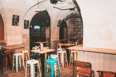 Salle voûtée en pierre avec des tables hautes, des tabourets colorés et un éclairage tamisé.