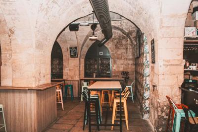 Salle voûtée en pierre avec des tables hautes, des tabourets colorés et un éclairage tamisé.