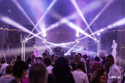 Foule dansant sous des jeux de lumière colorés lors d'une soirée festive en intérieur.