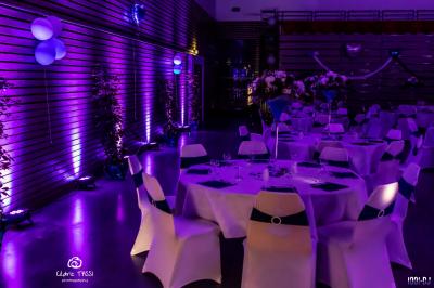 Foule dansant sous des jeux de lumière colorés lors d'une soirée festive en intérieur.