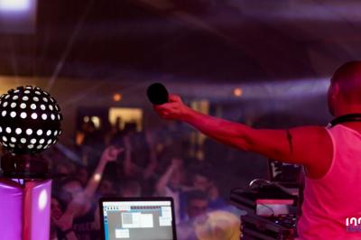 Foule dansant sous des jeux de lumière colorés lors d'une soirée festive en intérieur.