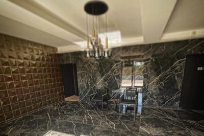 Salle de bain avec lavabo en pierre, trois miroirs dorés rectangulaires et murs en marbre aux motifs noirs et blancs.