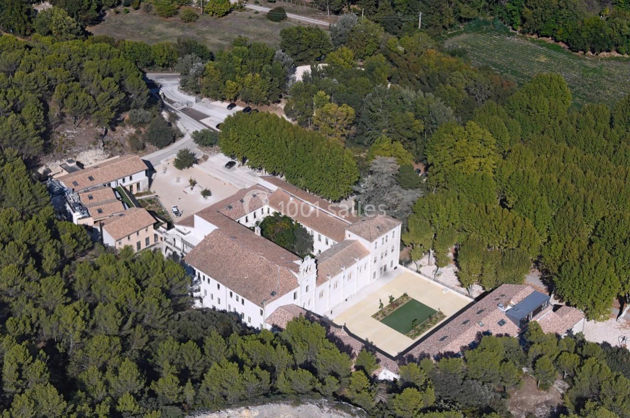 Vue aérienne d'un bâtiment historique entouré de végétation, avec une cour centrale et des toits en tuiles.