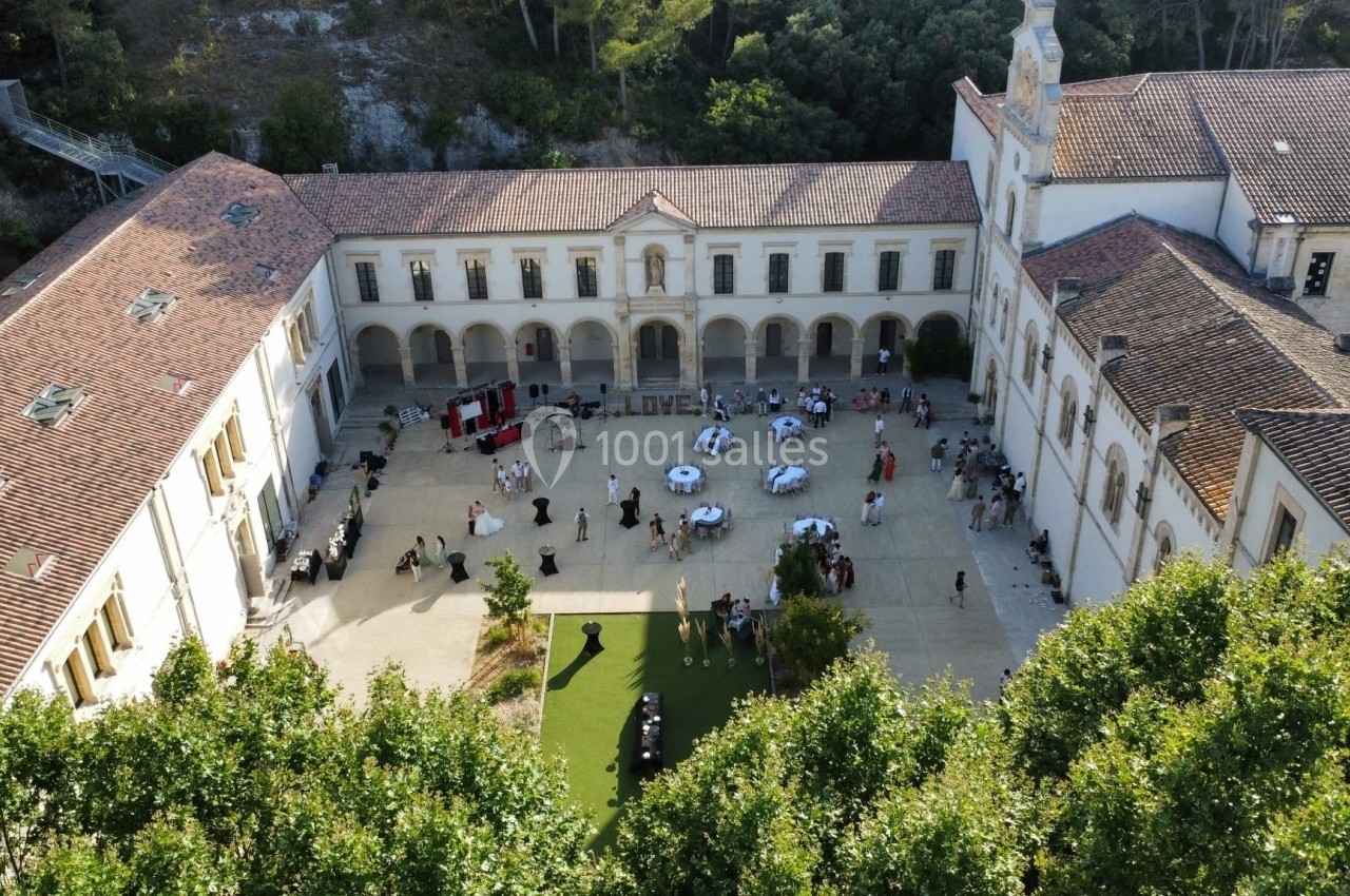 Vue aérienne d'une cour intérieure avec des tables dressées et des invités lors d'un événement en plein air.