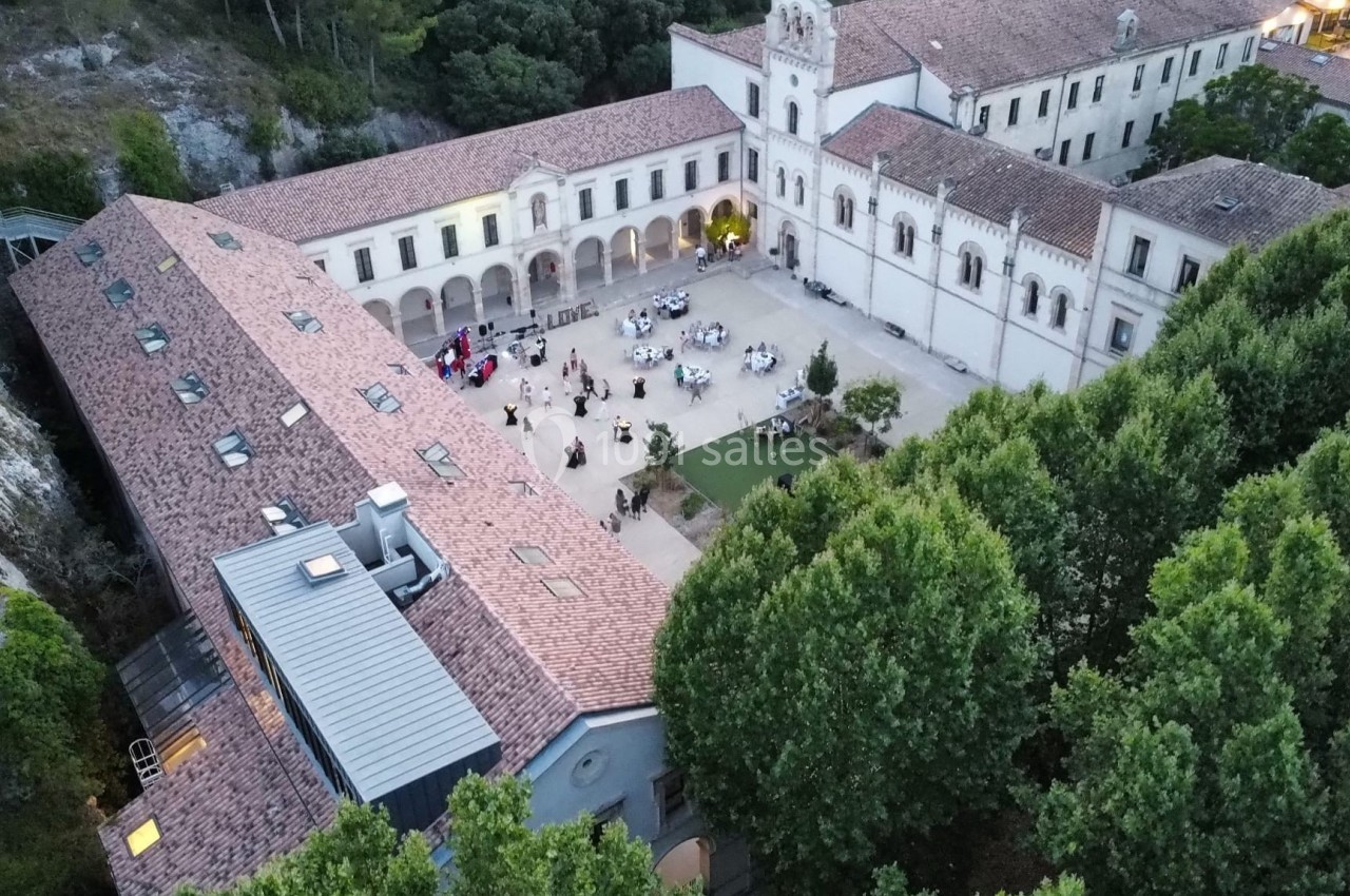 Vue aérienne d'un ancien monastère avec une cour centrale animée par des tables et des invités.