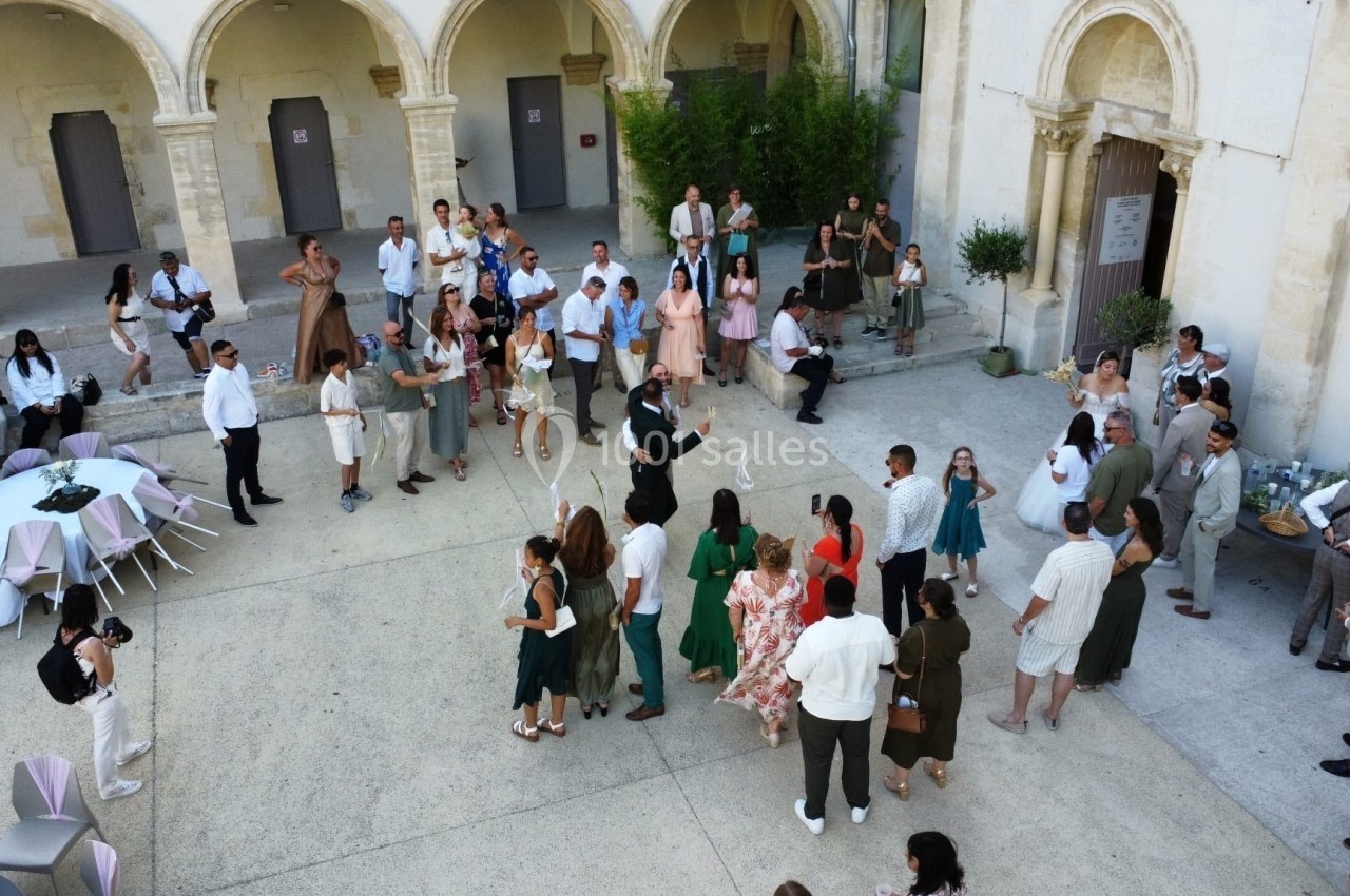 Groupe de personnes rassemblées dans une cour intérieure avec des arches, lors d'un événement convivial.