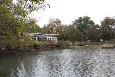 Parking vide en plein air entouré d'arbres, avec un panneau indiquant une zone de stationnement.