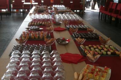 Bâtiment en briques avec de grandes baies vitrées, entouré d'arbres, près d'un plan d'eau sous un ciel dégagé.