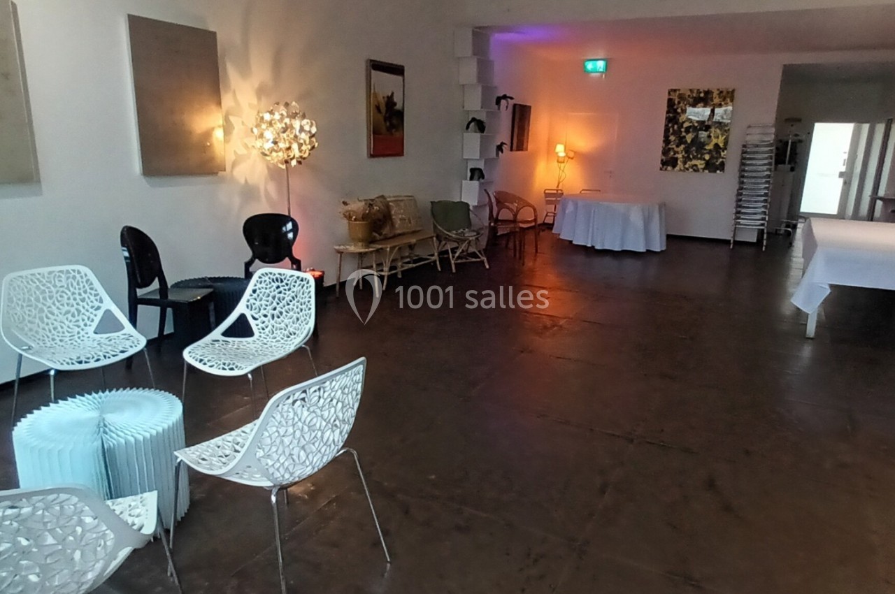 Salle lumineuse avec mobilier moderne, chaises design, tables blanches et éclairage d'ambiance chaleureux.